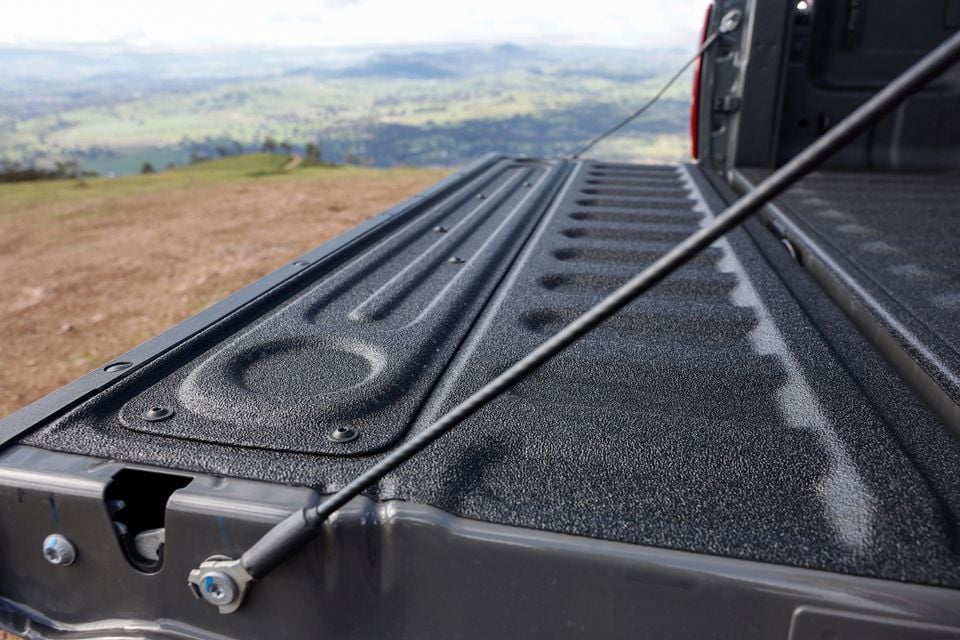 The tub liner of a Ram 2500 Warlock ute is shown with the tailgate open, overlooking a hilly landscape.