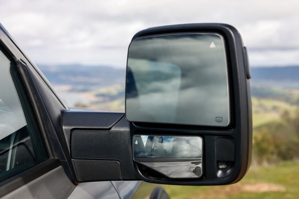 Close-up of the large towing side mirror on a Ram 2500 Warlock, with hills visible in the background