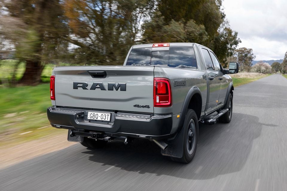 A grey Ram 2500 Warlock 4x4 ute driving away from the camera on a country road, seen from the rear quarter.
