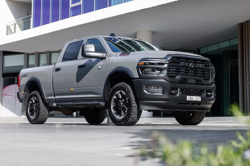 A grey Ram 2500 Warlock pickup truck parked outside a modern building, seen from the front side angle