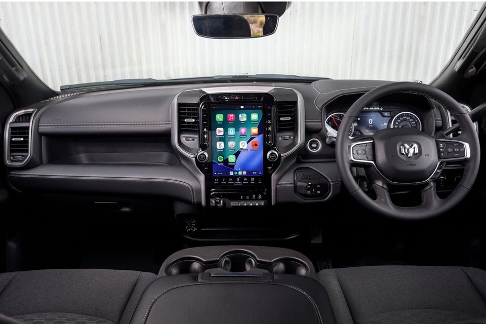 The dashboard and steering wheel inside a Ram 2500 Warlock, showing the vertical touchscreen infotainment display and instrument cluster