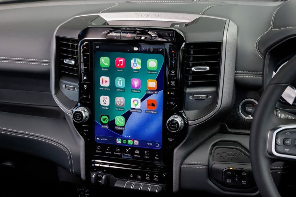 The vertical touchscreen infotainment display in a Ram 2500 Warlock showing Apple CarPlay with various app icons.