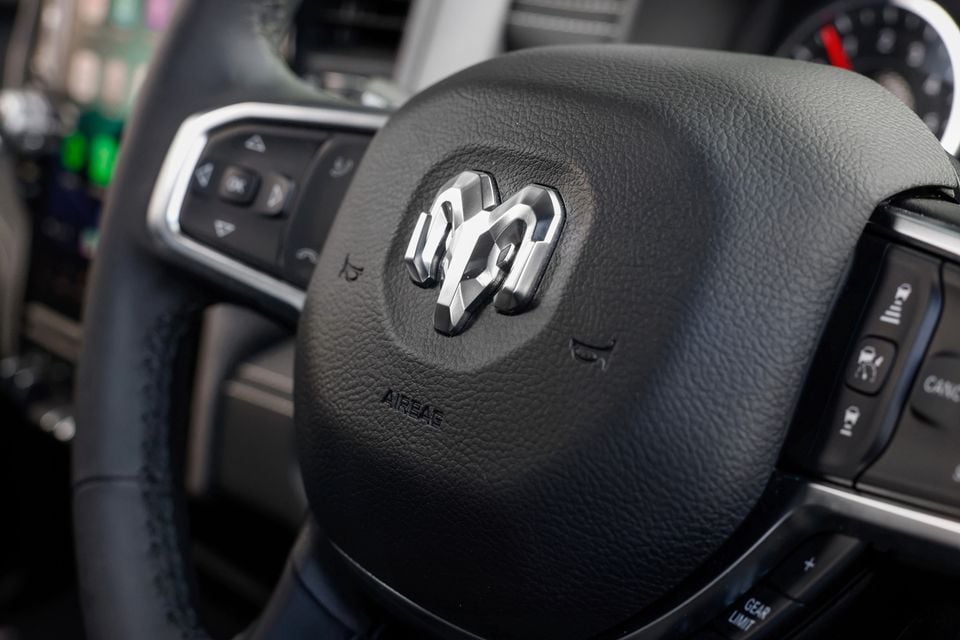 Close-up of the Ram logo on the steering wheel of a Ram 2500 Warlock, with control buttons visible nearby.