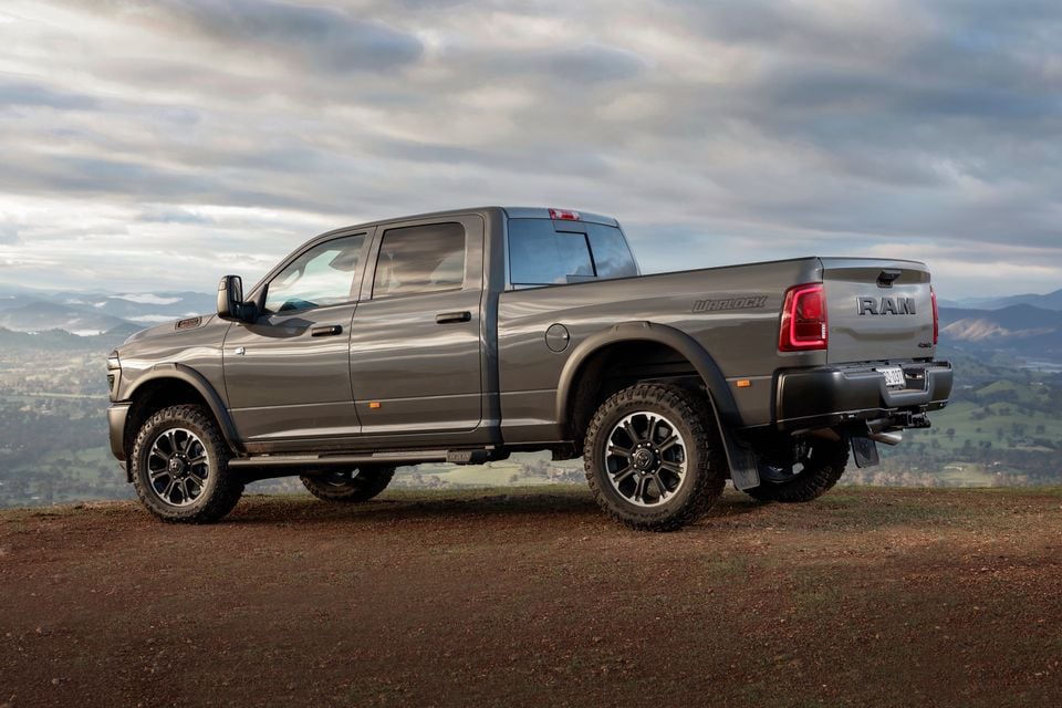 A grey 2026 Ram 2500 Warlock crew cab pickup truck parked on a hilltop, seen from the rear side angle.