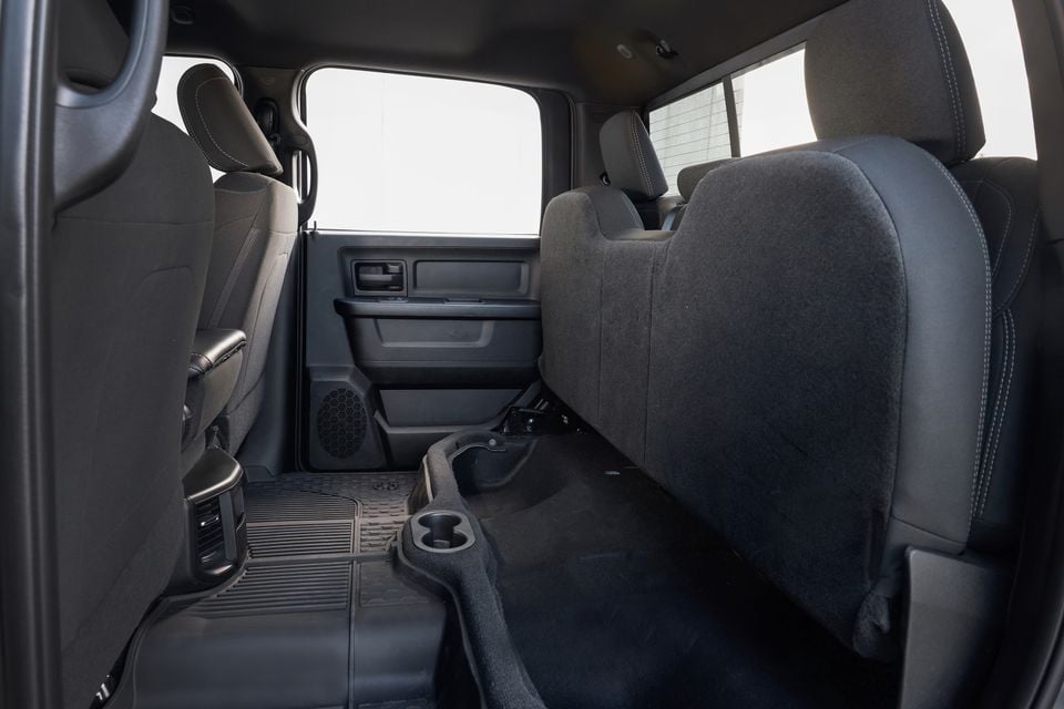 The rear seats and cabin of a 2026 Ram 2500 Warlock, showing black cloth upholstery and folded floor storage.