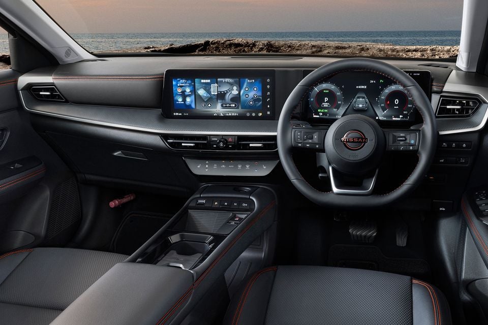 Nissan Kicks interior showing the dashboard, large touchscreen infotainment display, digital instrument cluster, steering wheel with Nissan logo, and centre console with orange contrast stitching on the seats