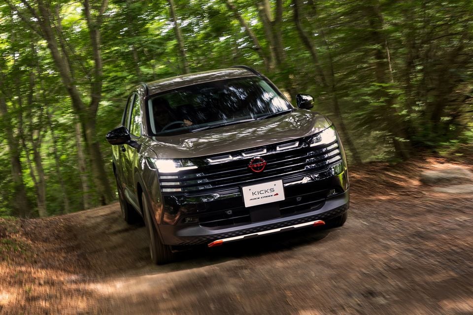 A Nissan Kicks Rock Creek SUV driving along a dirt forest trail, seen from the front