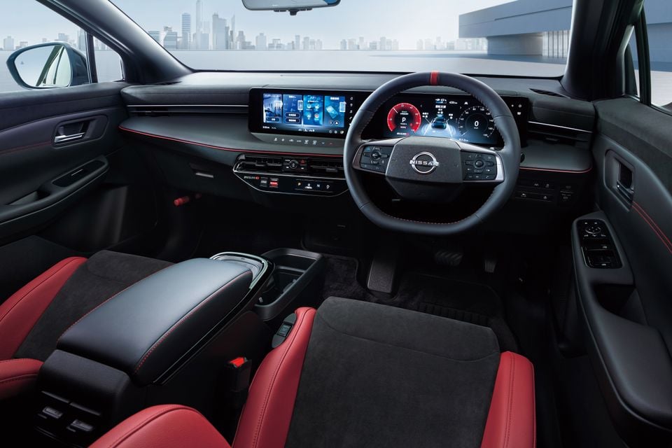 Nissan Leaf Nismo interior showing the dual digital screens, Nismo-branded dashboard, red and black leather seats, and Nissan steering wheel on the right-hand side