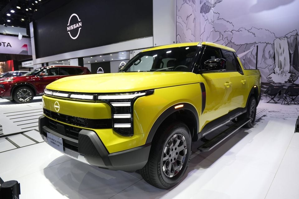 A yellow Nissan Navara Pro pickup truck on display at an indoor motor show, seen from the front quarter