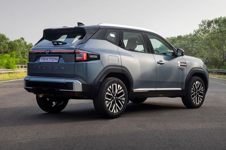 A grey Nissan Tekton SUV seen from the rear three-quarter angle on a road, showing its tailgate, alloy wheels and two-tone roof