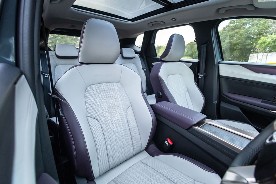 Two-tone white and purple leather front seats of the Nissan Tekna interior, with a panoramic sunroof visible above and captain-style rear seating in the background