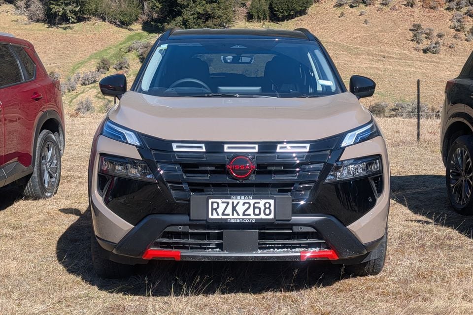 A beige Nissan X-Trail Rock Creek SUV parked on grass, viewed straight on from the front.