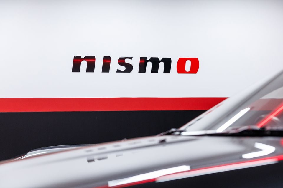 The Nismo logo displayed on a wall behind the hood of a white Nissan vehicle at a performance centre