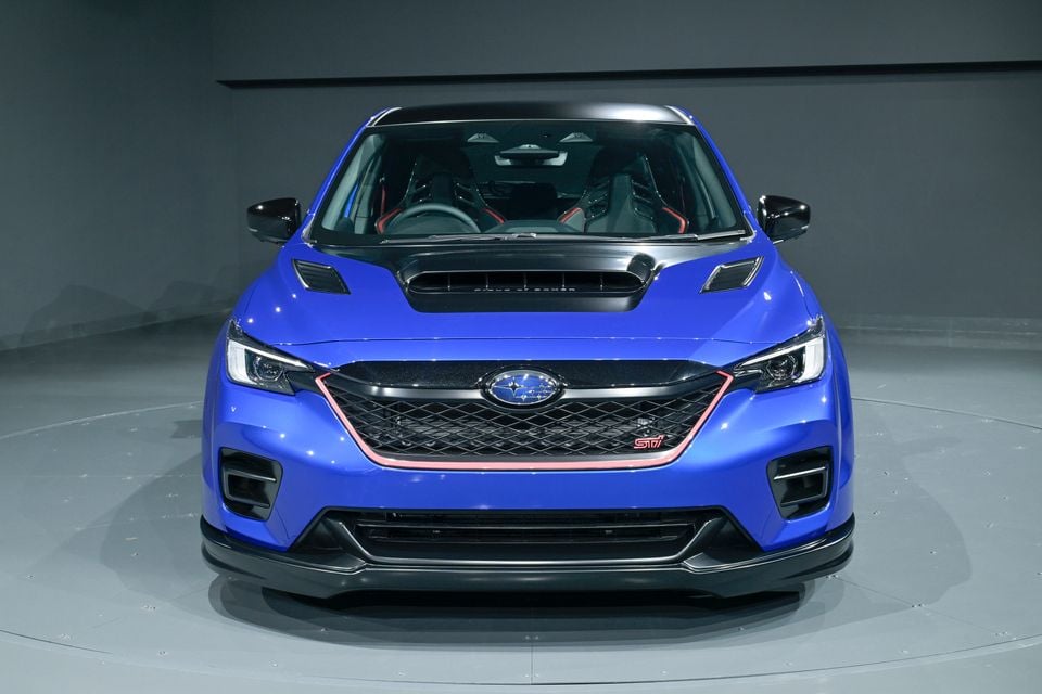 A blue Subaru WRX STI concept car seen from the front, displayed on a revolving stage indoors