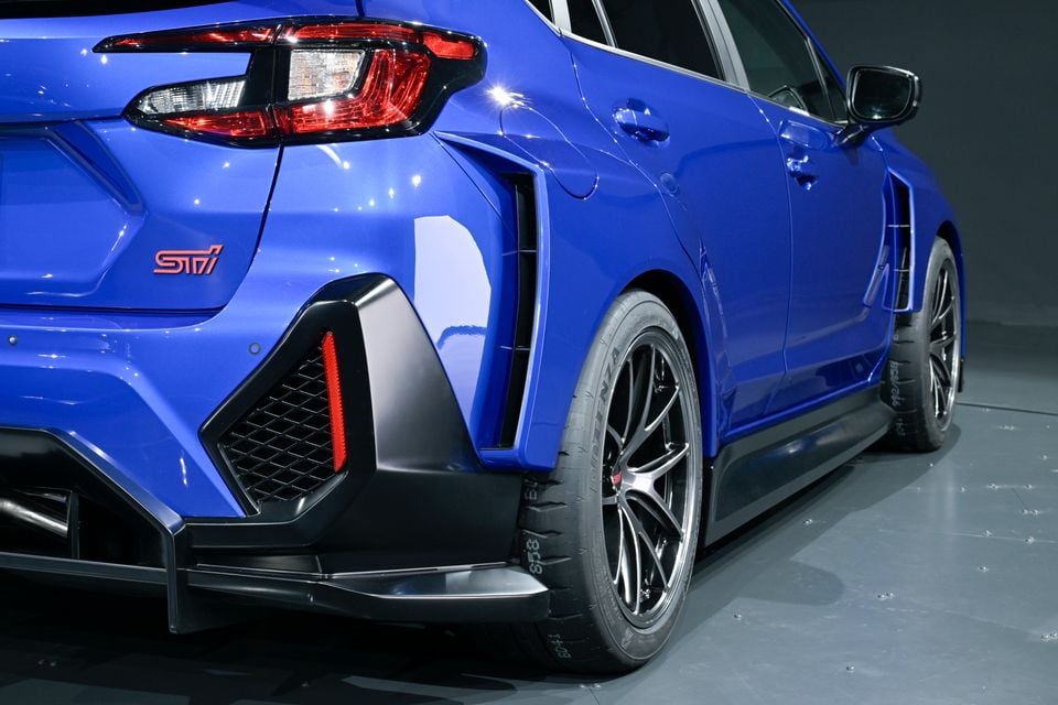 Rear quarter view of a blue Subaru STI concept car in a studio, showing the STI badge, tail light, rear diffuser, and alloy wheel