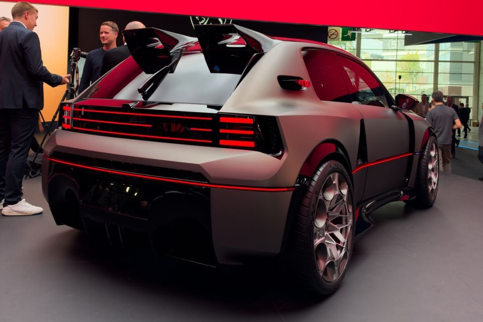 Peugeot E-T16 concept hatchback in matte grey with red lighting, seen from the rear on display at a motor show