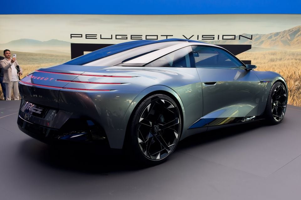 A silver-green Peugeot Vision RCZ concept coupe on display at a motor show, seen from the rear quarter with its red light bar and large black wheels