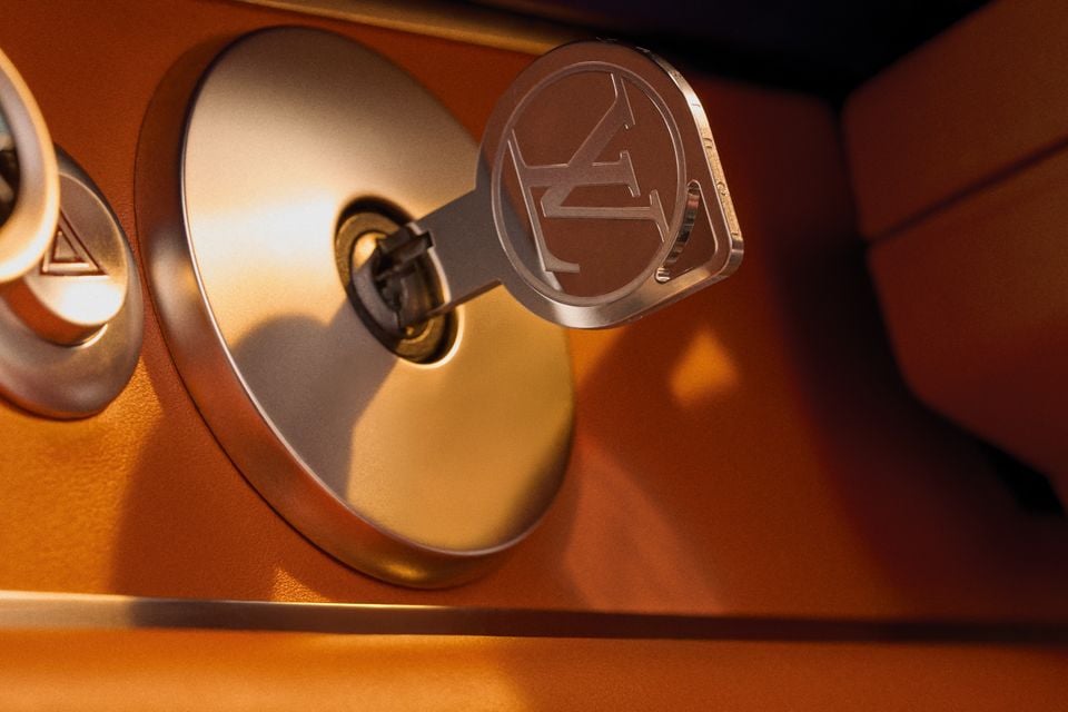A Louis Vuitton monogram-engraved key inserted into the ignition of a Porsche 911 reimagined by Singer, surrounded by tan leather interior detail