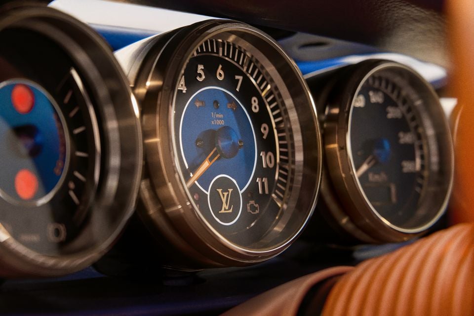 Close-up of the dashboard gauges in a Porsche 911 reimagined by Singer and Louis Vuitton, featuring a tachometer with the Louis Vuitton monogram logo on a blue dial face