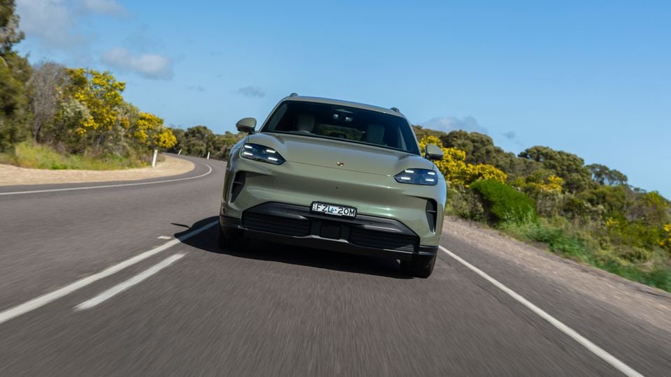 A green Porsche Cayenne S Electric SUV driving towards the camera on a country road in Australia