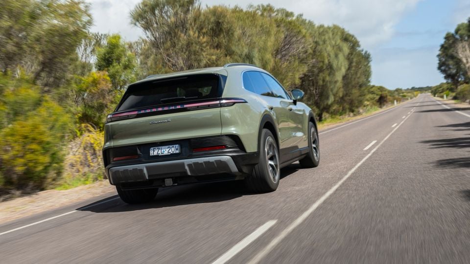 A green Porsche Cayenne S Electric SUV seen from the rear while driving on a rural road