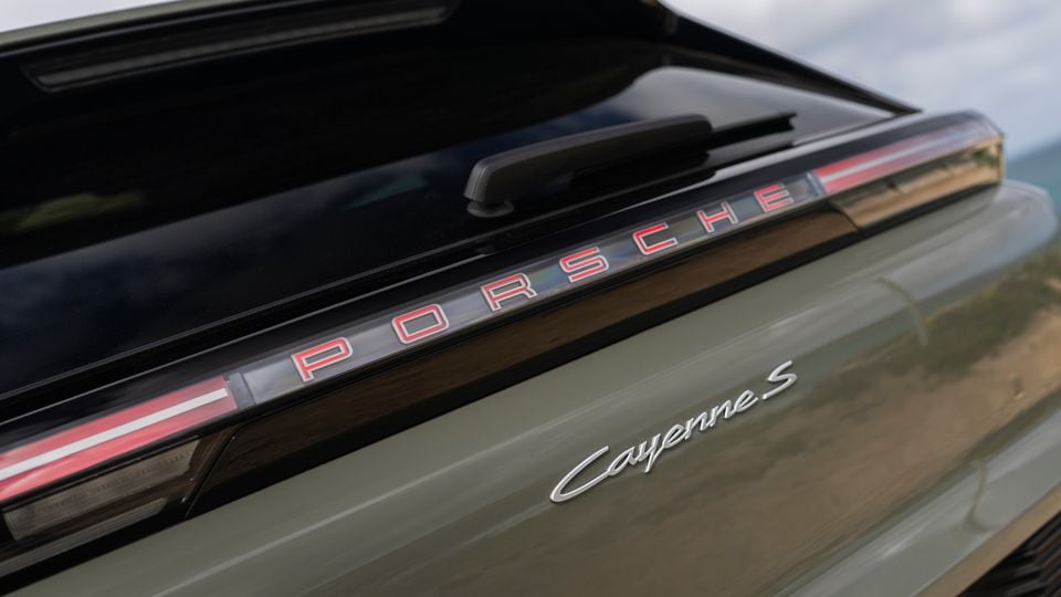 Close-up of the rear of a Porsche Cayenne S showing the illuminated Porsche lettering across the light bar and Cayenne S badge on the tailgate