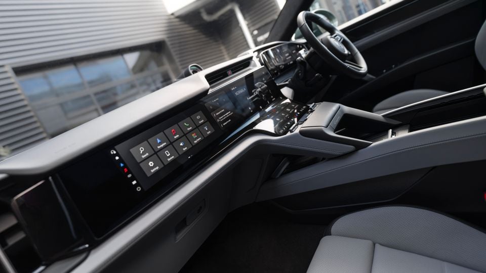 Interior of a Porsche Cayenne Turbo E-Hybrid showing a wide dual-screen infotainment display and centre console from the passenger side