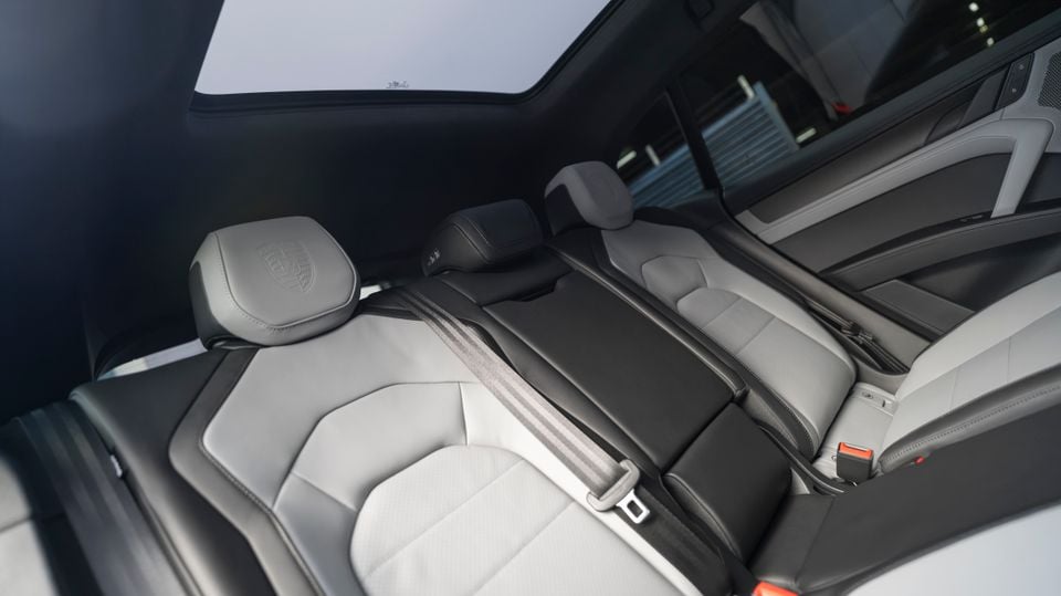 Porsche Cayenne Turbo E-Hybrid rear interior showing two-tone grey and black leather rear seats with Porsche-embossed headrests and a panoramic sunroof overhead