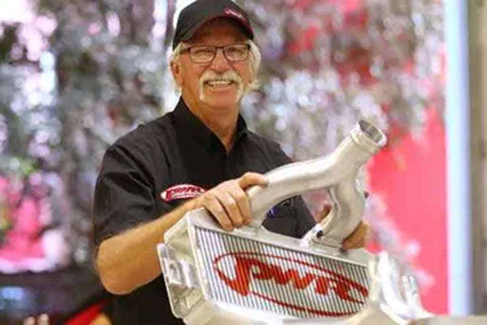 PWR Australia founder Kees Weel smiling while holding a PWR-branded aluminium intercooler with attached piping