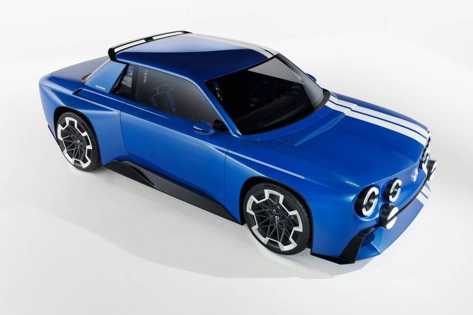 Um carro-conceito Renault 8 Gordini azul com listras de corrida brancas, mostrado de um ângulo frontal elevado em um fundo de estúdio branco