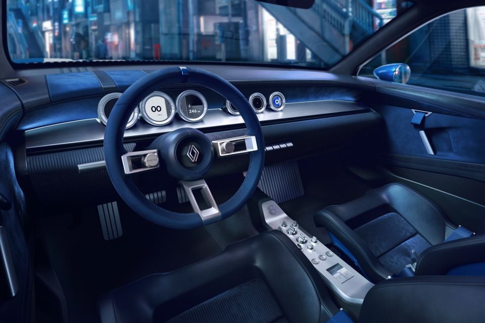 O interior em estilo retrô do conceito Renault 8 Gordini, mostrando um volante azul, medidores analógicos redondos e um console central distinto com interruptores.