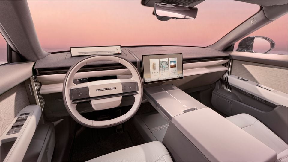 Range Rover GT interior showing the steering wheel, large central touchscreen infotainment display, and minimalist dashboard with light grey upholstery