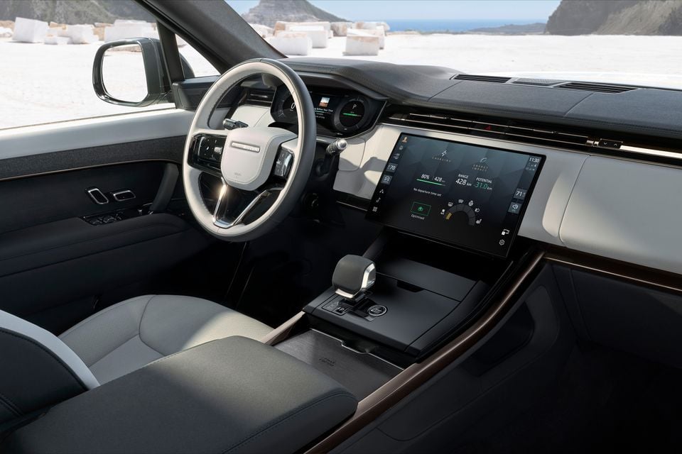 The interior of a Range Rover Sport electric SUV, showing the steering wheel, digital dashboard and centre touchscreen displaying charging and range information.
