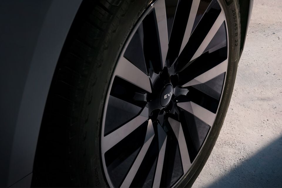 Close-up of a black and grey alloy wheel with an "EV" badge on the centre cap of an electric vehicle.