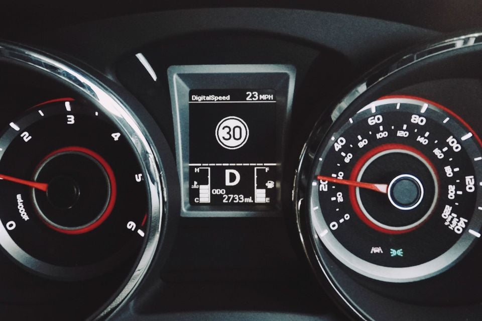 Close-up of a SsangYong Tivoli instrument cluster showing the speedometer, tachometer, and a central display with traffic sign recognition showing a 30 MPH speed limit sign, digital speed of 23 MPH, and odometer reading of 2733 miles.