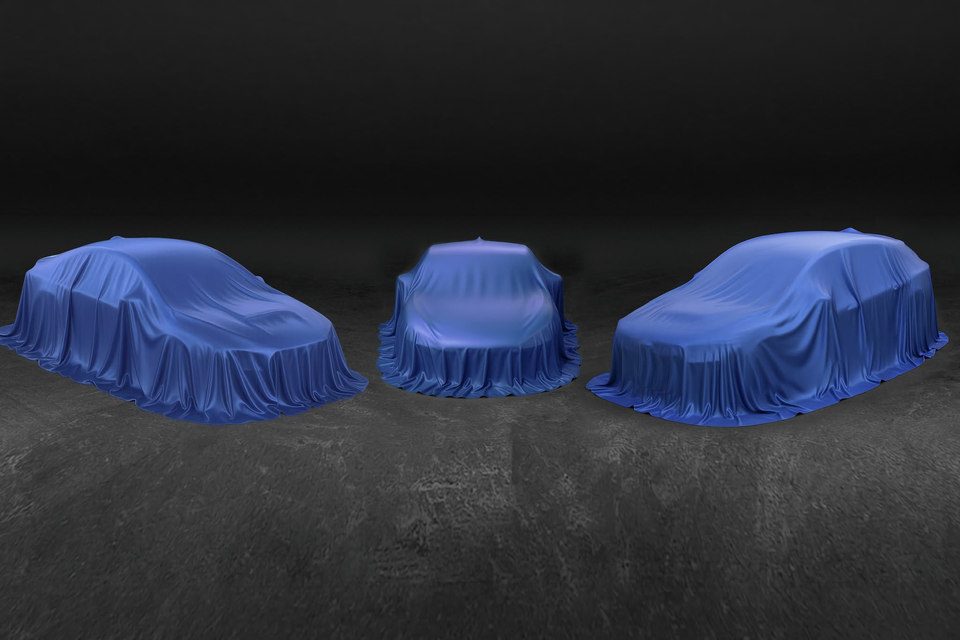 Three cars covered with blue satin sheets on a dark studio background, teasing upcoming unrevealed Subaru models