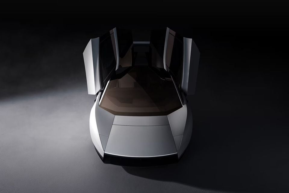 A silver Tesla concept car with its butterfly doors raised, seen from above the front in a dark studio