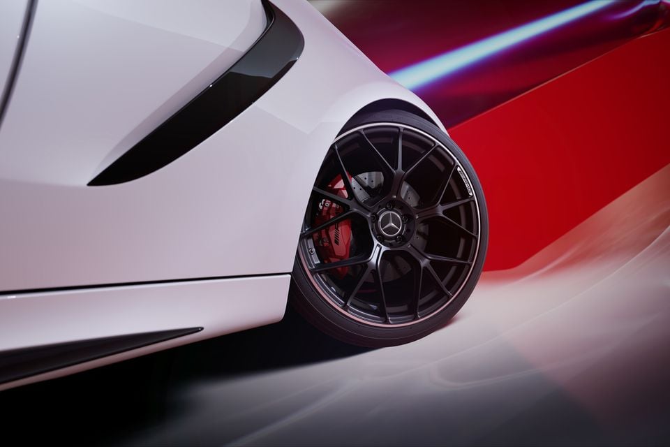Close-up of a Mercedes-AMG wheel with a dark multi-spoke rim and red brake calipers on a white sports car