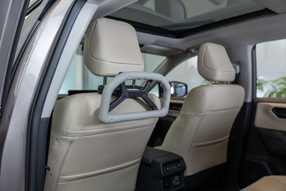 Interior of a Toyota showing cream leather seats with a mobility support handle attached to the front seat headrest, and a panoramic sunroof visible above