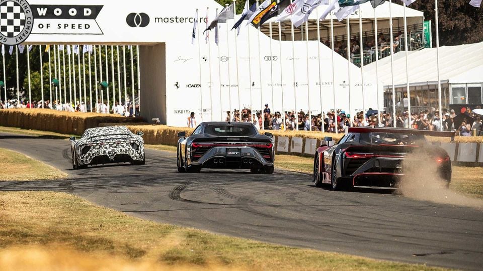Three high-performance sports cars, including a Toyota GR GT and GR GT3, seen from the rear as they drive up the hill at the Goodwood Festival of Speed, with crowds watching from the sidelines.