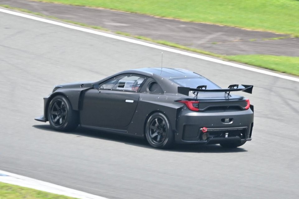 A black Toyota MR2 prototype race car seen from the rear three-quarter angle on a racing circuit, featuring a large rear wing and wide body kit
