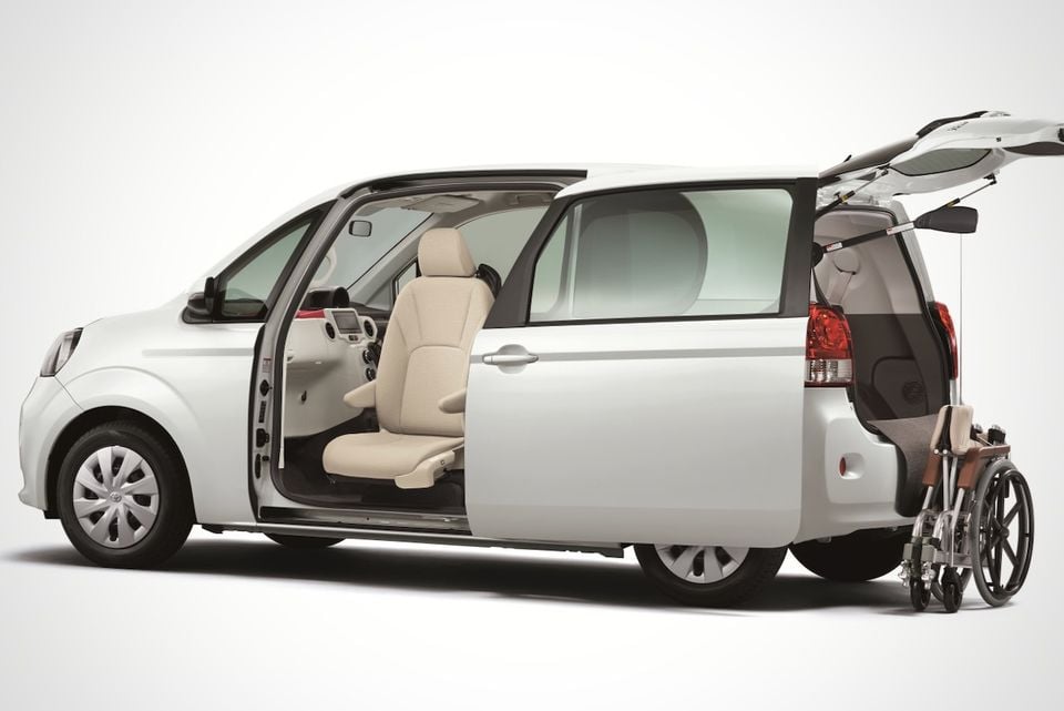 A white Toyota Porte wheelchair-accessible minivan shown from the side with the sliding door open and a wheelchair visible at the rear, on a white studio background.