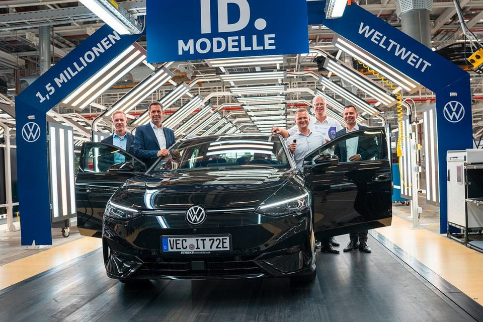 A black Volkswagen ID.5 electric car at a factory celebration marking 1.5 million ID. models produced worldwide, with five people posing alongside the vehicle.