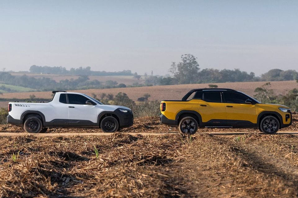 A white Volkswagen Taigun Robust single-cab ute and a yellow Volkswagen Taigun Extreme double-cab ute parked side by side on a dirt track in an open rural landscape