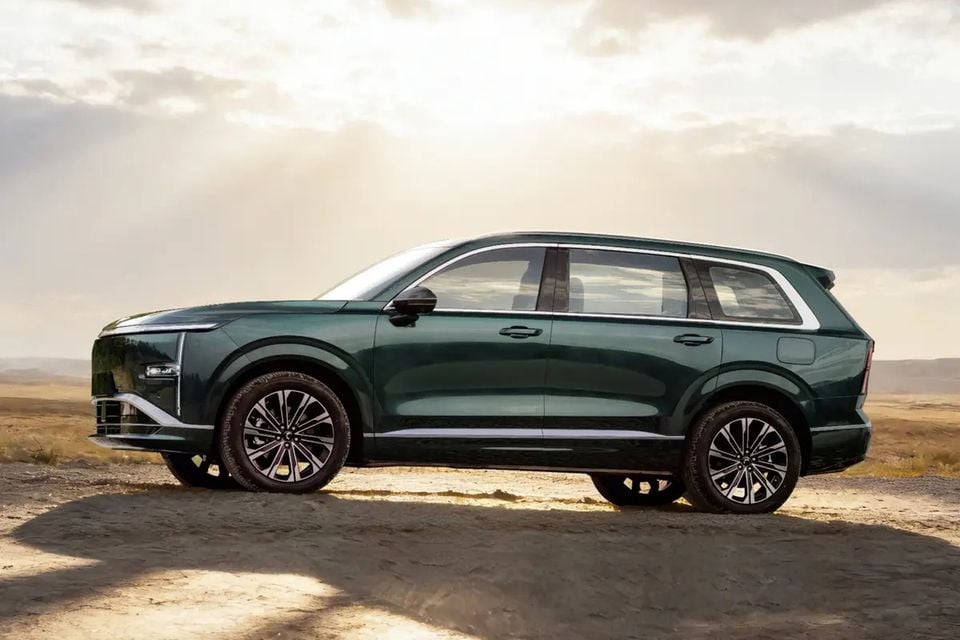 A dark green Wuling Starlight L SUV parked on dirt, seen from the side against a bright cloudy sky