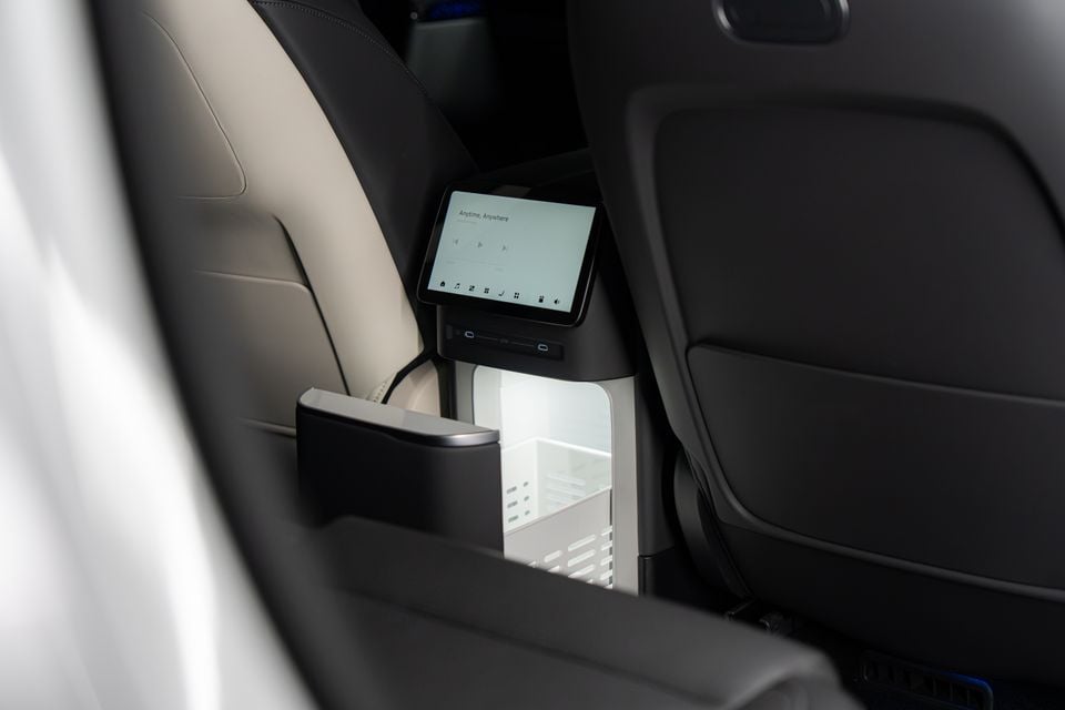 Rear-seat touchscreen and illuminated fridge between the front seats of an Xpeng G9 SUV, seen from the second row