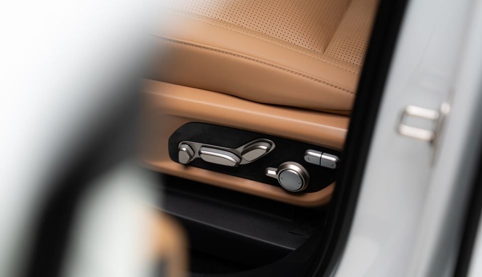 Power seat adjustment controls on the side of a tan leather front seat in an XPeng G9L, seen through the open door