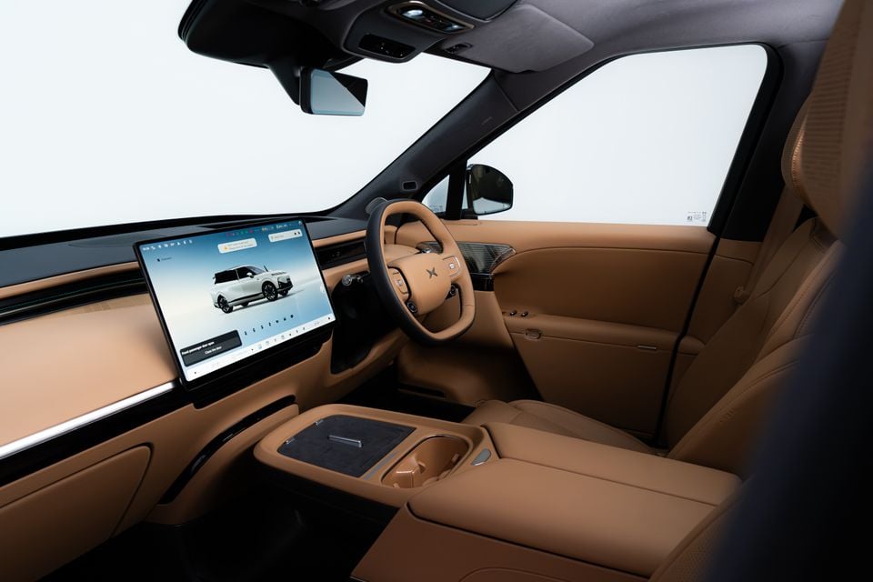 Tan leather front cabin of the XPeng G9L with a large central touchscreen, steering wheel and centre console, seen from the passenger side