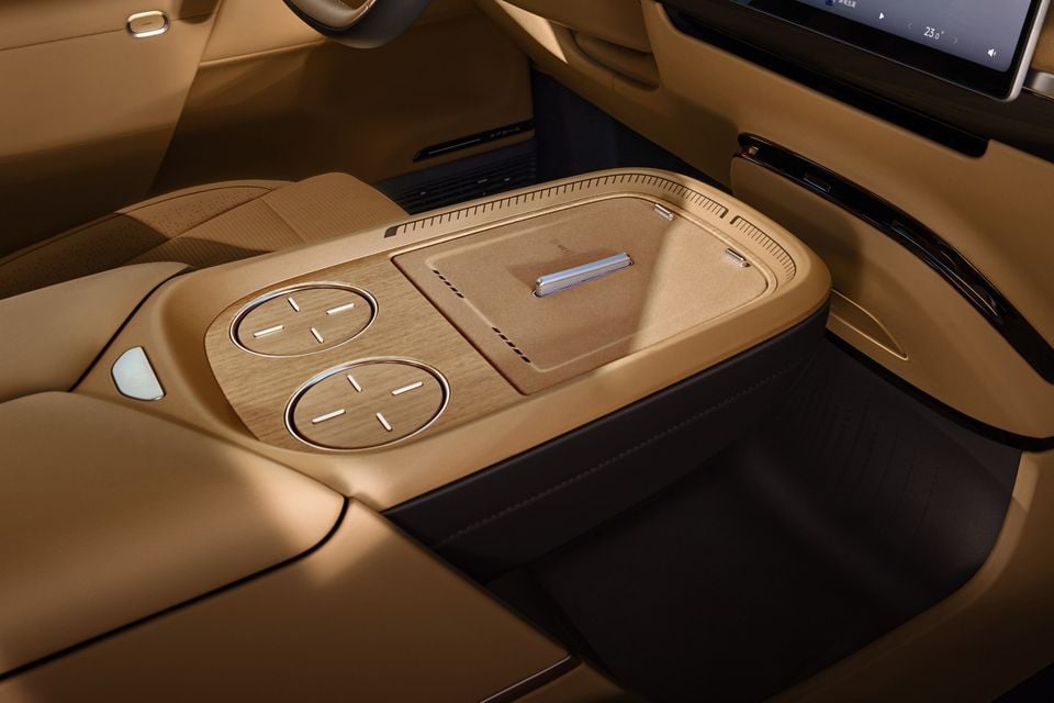 Interior centre console of the Xpeng G6 showing wood-trimmed wireless charging pads, storage compartment and rear passenger infotainment screen