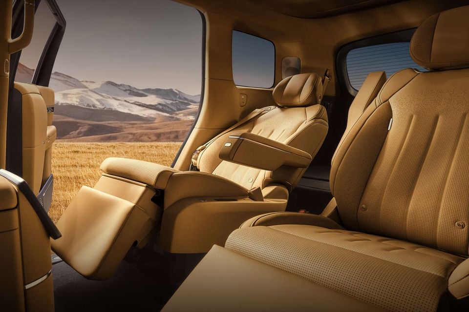 Tan leather rear interior of the Xpeng G9 showing reclining captain's chairs with a scenic mountain and grassland view through the open door